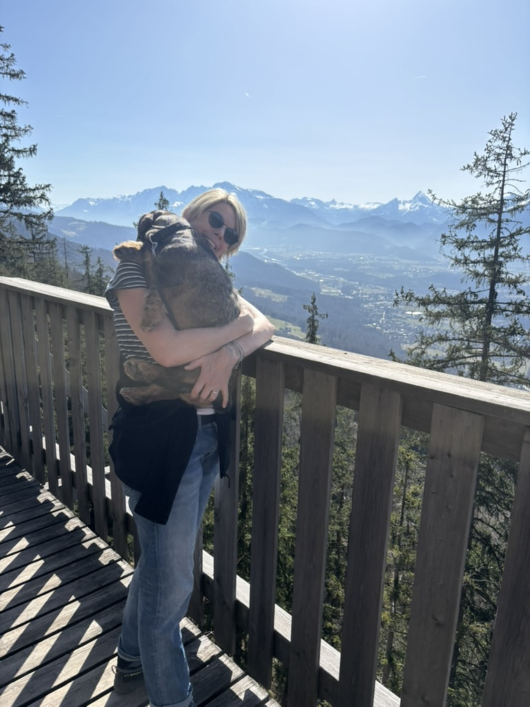 Sylvia Eberl mit Hund auf dem Arm am Gaisbergsteg bei Salzburg, Blick auf die Alpen.